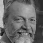 Black and white headshot of a bearded man.